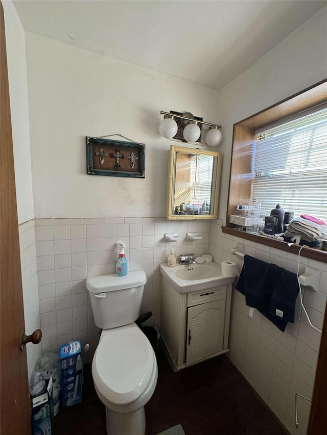 bathroom with a wainscoted wall, toilet, tile walls, and vanity