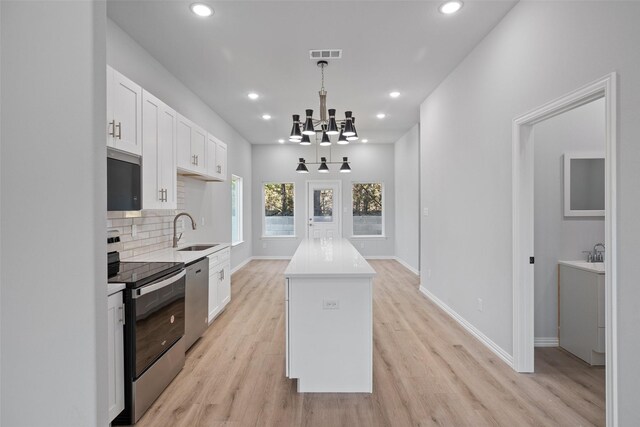 kitchen with visible vents, a sink, decorative backsplash, appliances with stainless steel finishes, and a center island