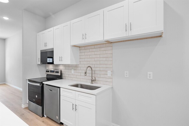 kitchen featuring tasteful backsplash, white cabinets, appliances with stainless steel finishes, and a sink