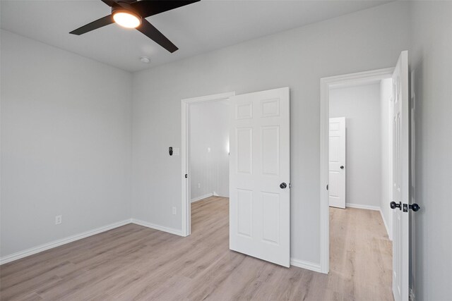 unfurnished bedroom featuring light wood-style flooring, a ceiling fan, and baseboards