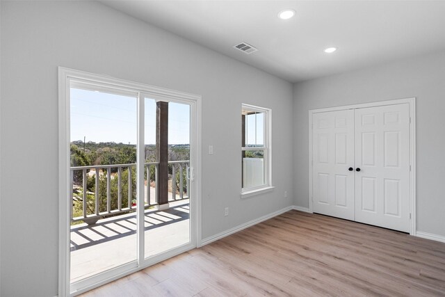 unfurnished bedroom with access to outside, wood finished floors, recessed lighting, a closet, and baseboards