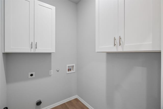 laundry area featuring electric dryer hookup, washer hookup, wood finished floors, hookup for a gas dryer, and cabinet space