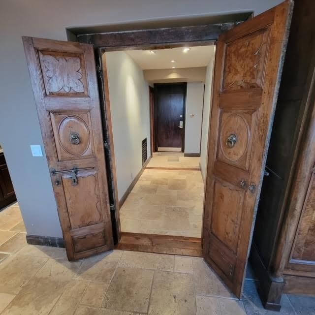 corridor featuring visible vents, baseboards, and stone tile flooring