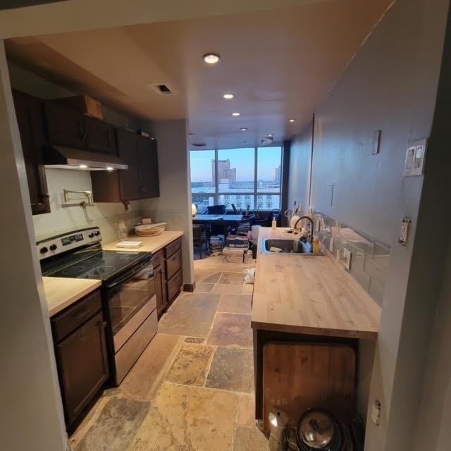 kitchen featuring electric range, a sink, stone tile floors, light countertops, and extractor fan