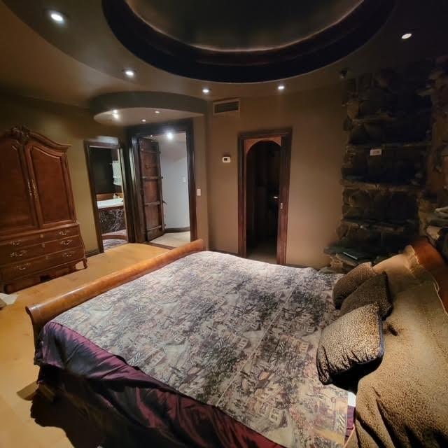 bedroom with a tray ceiling, recessed lighting, and visible vents