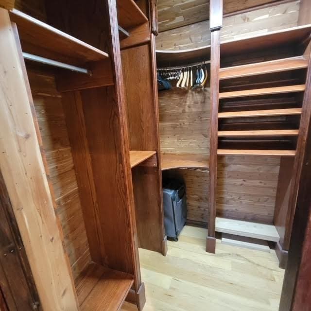 walk in closet with wood finished floors