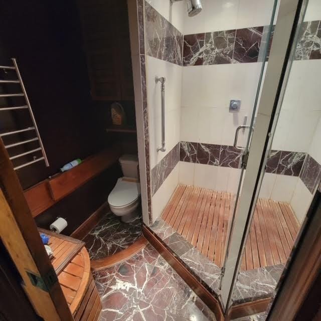 bathroom featuring a shower stall and toilet