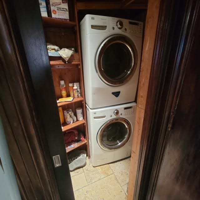 laundry room featuring stone tile floors, laundry area, and stacked washer / dryer