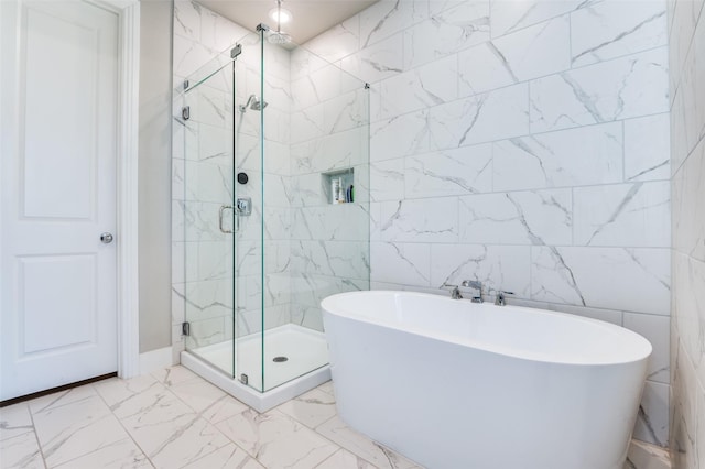 bathroom with marble finish floor, a soaking tub, a stall shower, and tile walls