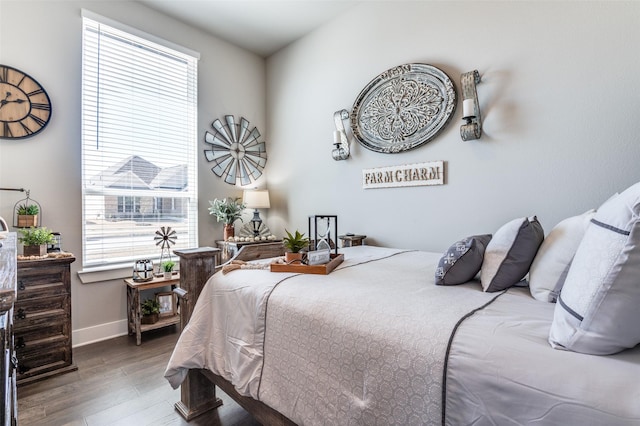 bedroom with wood finished floors, baseboards, and multiple windows