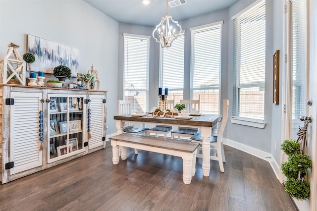 dining space with dark wood-style flooring, a healthy amount of sunlight, a notable chandelier, and baseboards