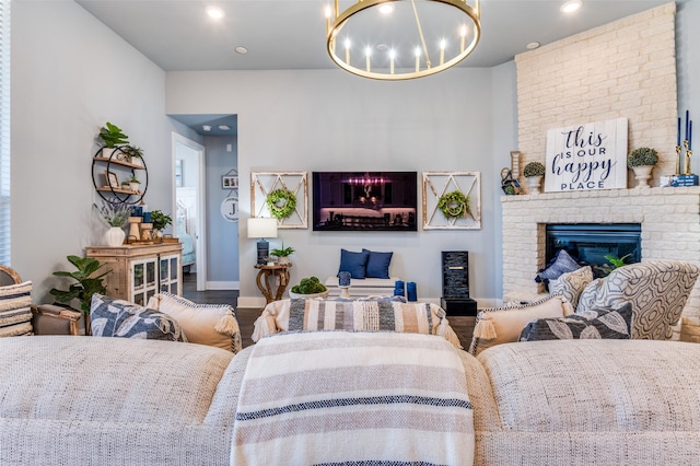 living room featuring recessed lighting, wood finished floors, an inviting chandelier, a brick fireplace, and baseboards
