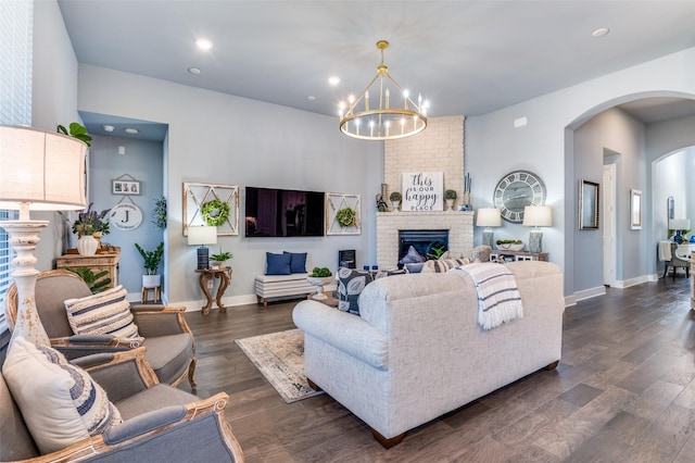 living area with a notable chandelier, dark wood-style floors, arched walkways, a fireplace, and baseboards