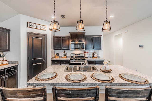 kitchen with visible vents, a kitchen bar, decorative backsplash, stainless steel appliances, and a sink