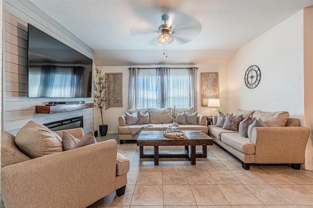 living area featuring light tile patterned floors, baseboards, a ceiling fan, and vaulted ceiling