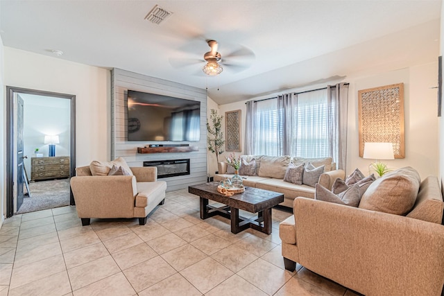 living room with light tile patterned floors, visible vents, ceiling fan, and a fireplace