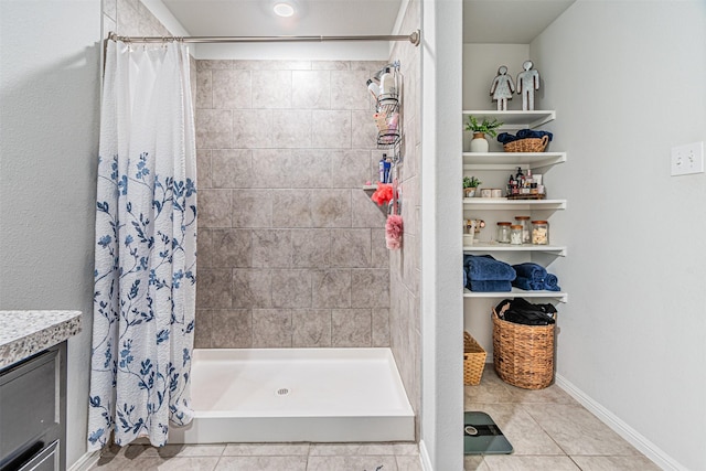 bathroom featuring tile patterned flooring, a stall shower, and baseboards