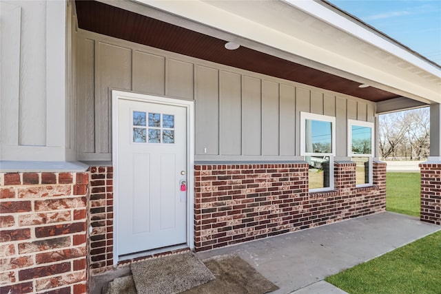 doorway to property with board and batten siding and brick siding