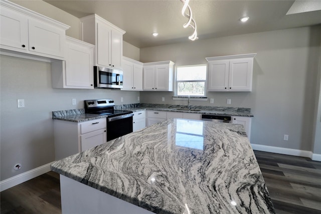 kitchen featuring white cabinets, light stone countertops, appliances with stainless steel finishes, and a sink