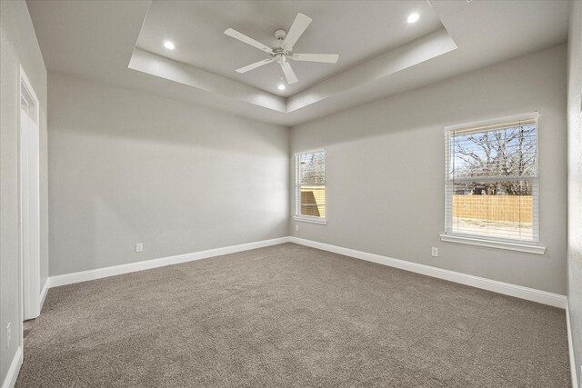 carpeted spare room featuring recessed lighting, a tray ceiling, and baseboards