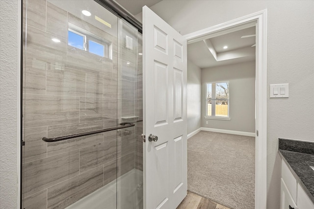 full bath featuring recessed lighting, tiled shower, vanity, and baseboards