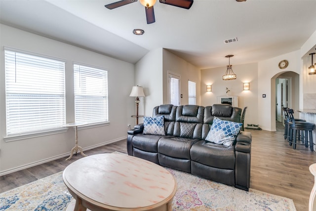 living area with wood finished floors, arched walkways, visible vents, and a healthy amount of sunlight