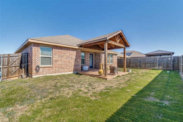 rear view of house with a patio area, a fenced backyard, a yard, and brick siding