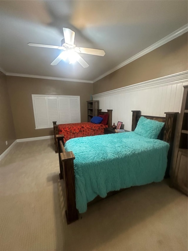 carpeted bedroom with baseboards, ornamental molding, and a ceiling fan