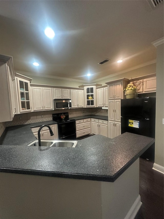 kitchen with dark countertops, black appliances, glass insert cabinets, and ornamental molding