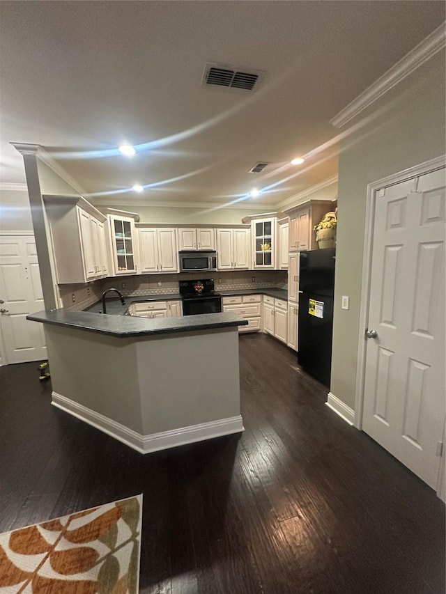 kitchen featuring dark countertops, visible vents, a peninsula, and black appliances