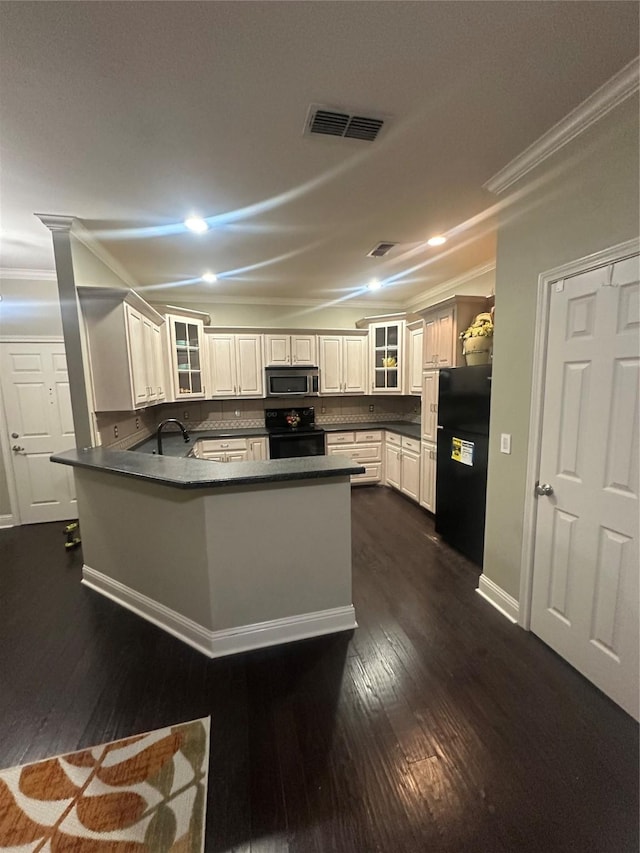 kitchen with dark countertops, visible vents, ornamental molding, a peninsula, and black appliances