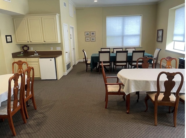 dining area with visible vents, baseboards, dark colored carpet, and ornamental molding