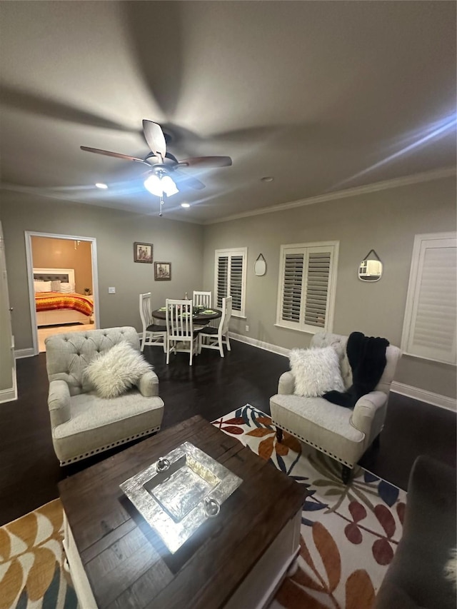 living area with dark wood-style floors, a ceiling fan, crown molding, and baseboards