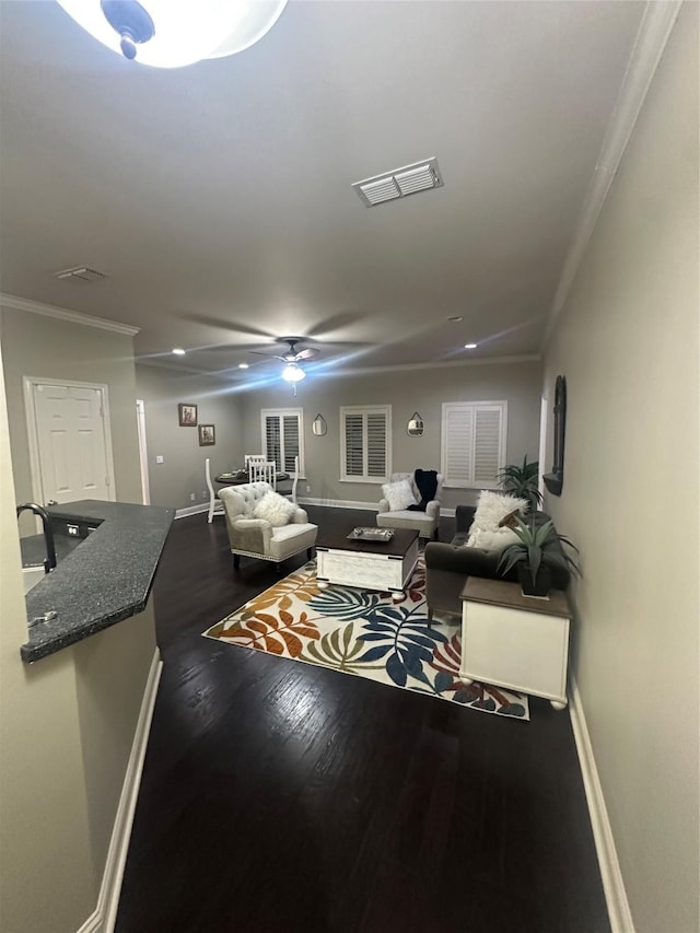 living room with a ceiling fan, baseboards, visible vents, dark wood finished floors, and crown molding