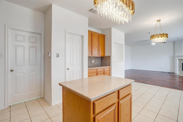 kitchen with decorative backsplash, light tile patterned floors, visible vents, and a chandelier