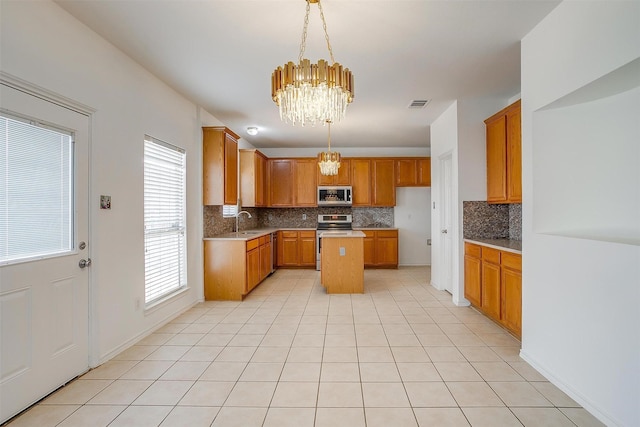 kitchen with visible vents, a sink, appliances with stainless steel finishes, a notable chandelier, and brown cabinets