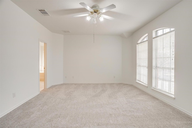 carpeted spare room featuring visible vents, baseboards, and ceiling fan