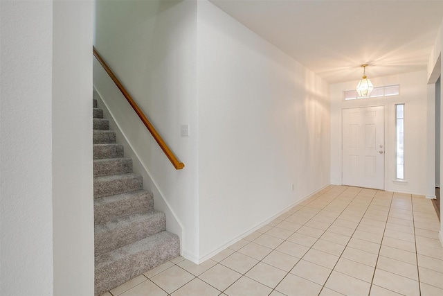 foyer featuring stairway, light tile patterned flooring, and baseboards