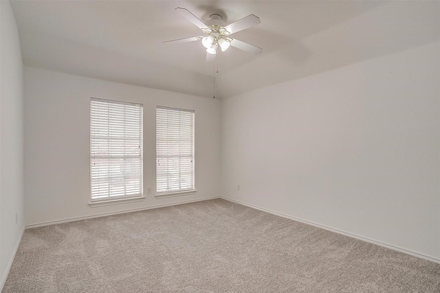 carpeted spare room featuring baseboards and a ceiling fan