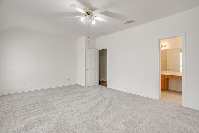 unfurnished bedroom featuring visible vents, light carpet, connected bathroom, ceiling fan, and vaulted ceiling