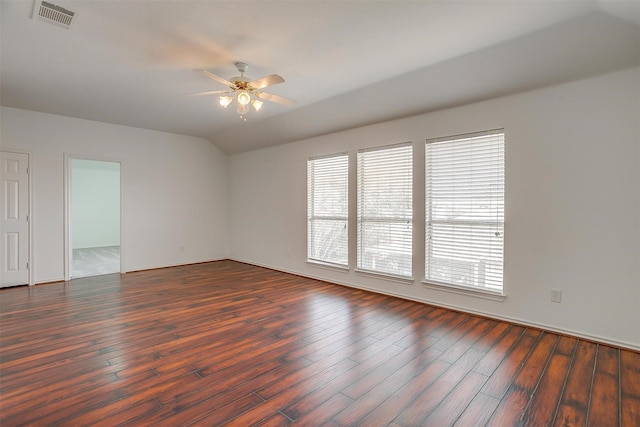 empty room with ceiling fan, visible vents, dark wood finished floors, and vaulted ceiling