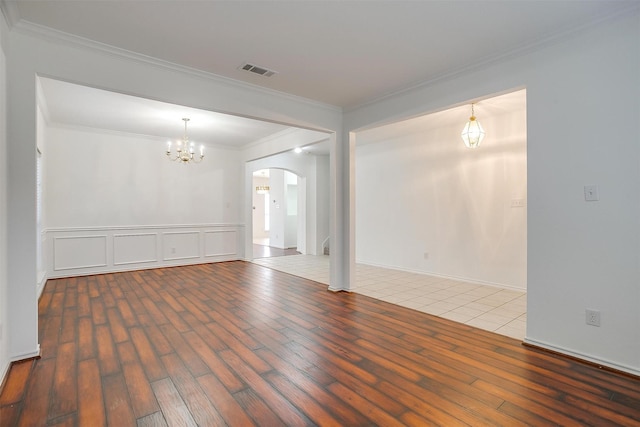 spare room with visible vents, arched walkways, wood finished floors, and ornamental molding