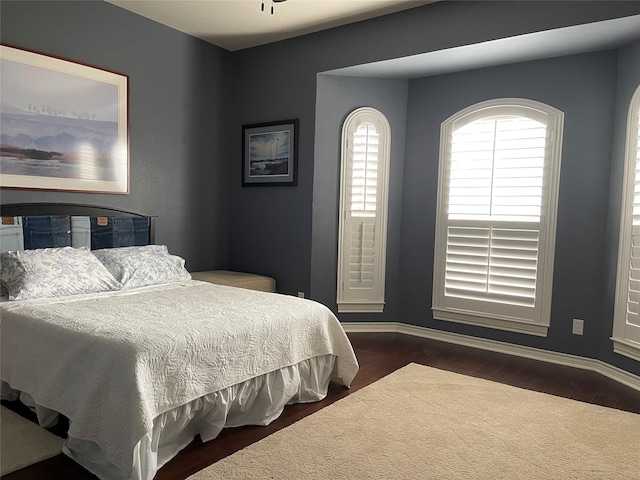 bedroom with baseboards and dark wood-type flooring