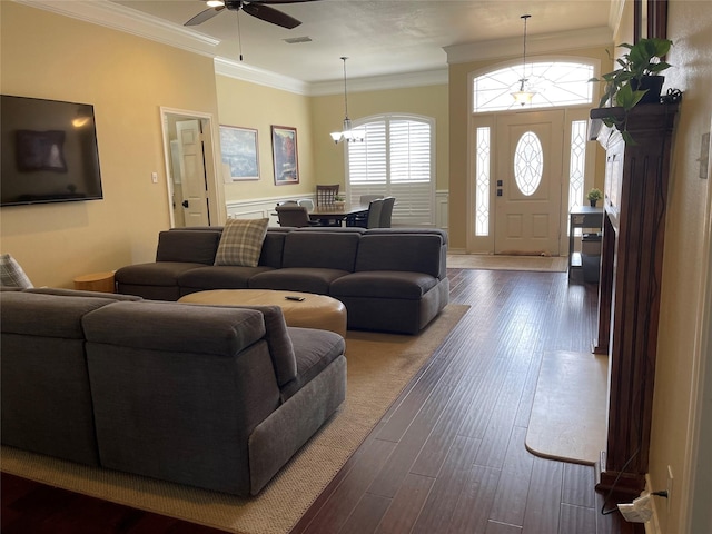 living area featuring dark wood-style floors, visible vents, ceiling fan with notable chandelier, and ornamental molding