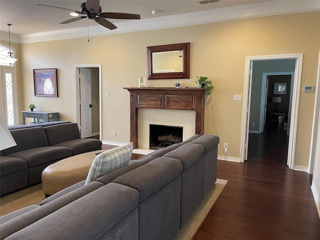 living room featuring crown molding, ceiling fan, baseboards, dark wood-type flooring, and a fireplace with flush hearth