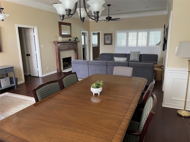 dining room featuring dark wood-style floors, a fireplace with flush hearth, ceiling fan with notable chandelier, and crown molding