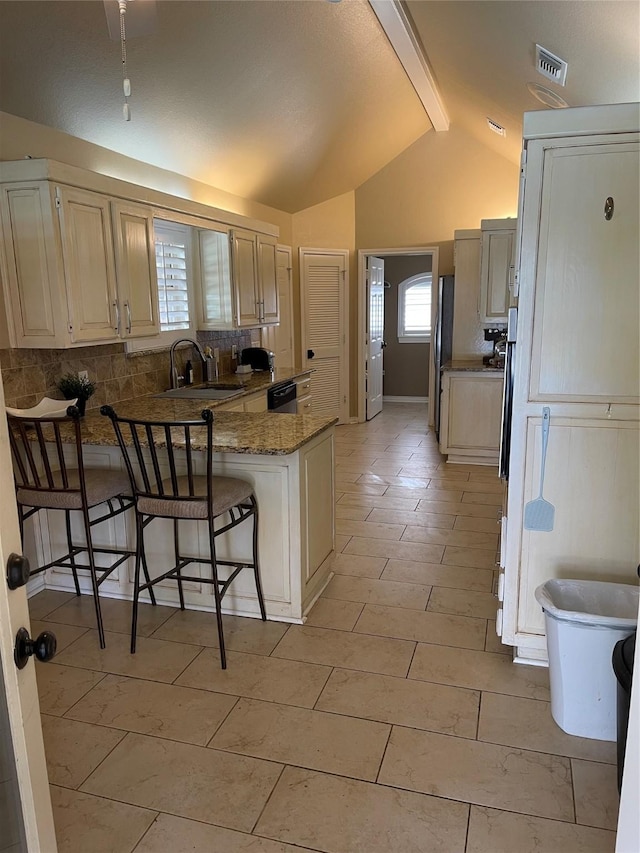 kitchen featuring visible vents, a peninsula, a sink, a kitchen breakfast bar, and backsplash