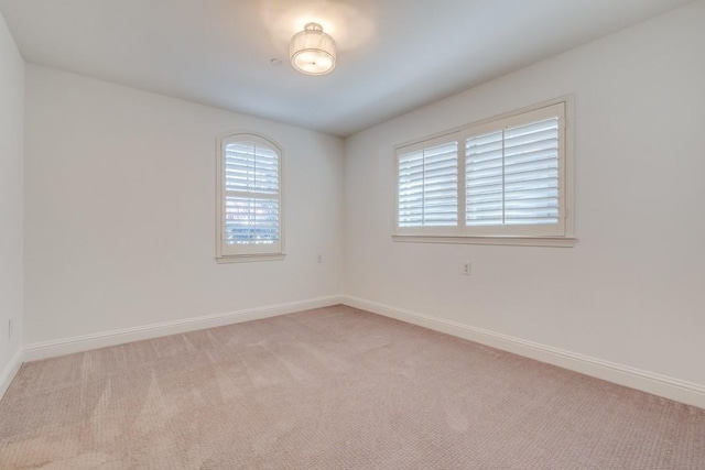 empty room with baseboards and light colored carpet