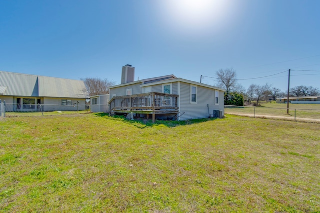 rear view of house featuring a deck, a yard, fence, and a chimney