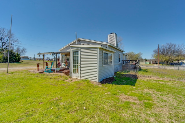 view of home's exterior featuring a chimney, a yard, and fence